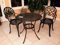 Full bistro set with round table and two chairs featuring lattice and scrollwork design