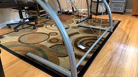 Area rug on hardwood floor showing curved black legs of furniture and part of a rolling chair.