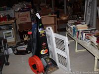 Wide view of all lot items showing the Bissell ProHeat shampooer with orange extension cord on the side and folded white plastic safety gate.