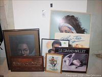 Overview photo showing all seven pieces of wall art arranged on the floor leaning against a wall; includes the Last Supper relief, signed prints, and ballet-themed prints.