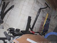 Photo showing the Bowflex weight bench and parts of the Solo Flex machine in a basement setting with concrete block walls.