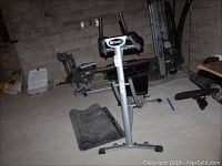 AbCoaster Pro exercise machine with black floor mat rolled beside it on the floor