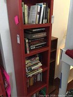 Tall red shelving unit with many books stacked on four shelves. Titles include books on black history and literature.
