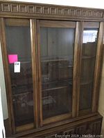Front view of china cabinet showing three glass doors revealing interior shelves for display.