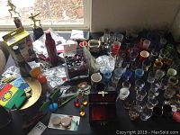 Overview of various items on table including trophies, shot glasses, a jewelry box, several small packaged items, floral beads, and watch bands.