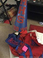 Megaphone with MHS red letters and year 90 '91, and cheerleading uniform pieces inside a plastic bin.