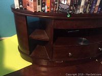 Close-up of the curved front dark wood coffee table showing the open shelves on the left side and wood grain finish.