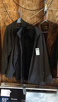 Three men's coats hanging on hangers on a wall; includes dark brown suede Cresco jacket, brown St John Bay jacket, and black Weatherproof jacket