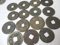 Top-down photo showing 15 varied Qing Dynasty coins with square holes, some lighter and some darker with varying degrees of patina and wear.