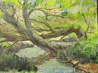 Close up photo showing textured oil paint landscape with greens and browns, depicting trees overhanging a river.