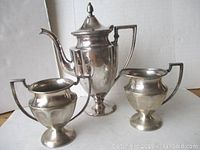 Three-piece coffee service set including coffee pot, creamer, and sugar bowl with visible tarnishing and wear.