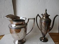 View of both silver plated items showing overall shape and condition, including the water pitcher monogram and coffee pot with lid.