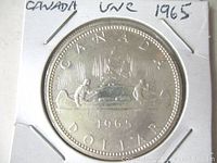 Obverse view of the Canada 1965 silver dollar coin inside a white 2x2 coin holder with handwritten notes.