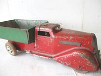 Side view showing red pressed steel cab and green dump bed with original wooden wheels and attached string at the front bumper.
