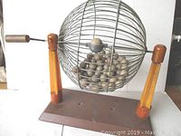 Front view of complete bingo cage assembly on wooden base.