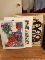Three framed artworks leaning against wall showing overview of lot