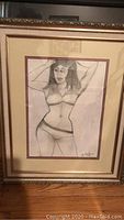 Framed sketch of a woman in lingerie signed by Jenik Cook shown from the front with gold frame and double matting