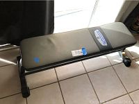 Side view of Iron Grip Strength weight bench with padded vinyl upholstery on tile floor