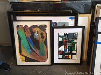Group shot of multiple framed abstract paintings leaning against wall