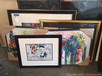 Overview of five framed artworks stacked against wall, two in front and three behind