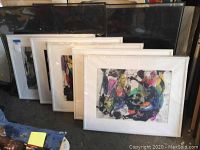 Five framed abstract artworks by Jenik Cook in white mats and frames, leaning against wall