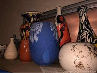Overview of all nine painted ceramic pieces on shelf