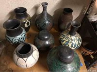 Overview of all eight raku-style vessels arranged on wooden surface