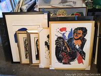 Group shot of five framed artworks stacked on floor