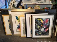 Wide shot showing all five framed artworks leaning against wall