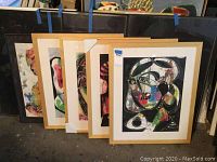 Five framed artworks leaning against wall