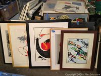 Wide shot of all five framed artworks leaning against storage crate
