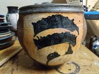 Full view of pot showing black abstract brushstroke design on tan clay body