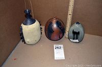 Frontal view of three vases side by side with ruler