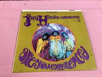 Front cover of The Jimi Hendrix Experience vinyl record with yellow and purple psychedelic design and band photo.