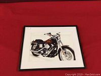 Framed picture showing full view of Harley Davidson motorcycle artwork in a simple dark frame on a red background.