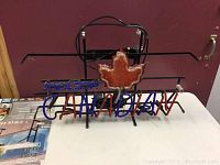 Front view of Molson Canadian neon sign showing blue and red lettering and a red maple leaf in the center on a black metal frame.