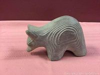 Image showing side profile of the bear sculpture with visible textured grooves and wear.