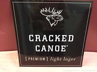 Full view of the Cracked Canoe beer advertising sign with moose head logo and brand text on black background.