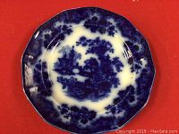 Top-down photo showing full view of octagonal Flow Blue china plate with blue landscape pattern and mold marks in the glaze.