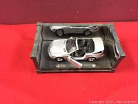 Silver 1:18 scale Mercedes Benz SL Class diecast model in black display case with mirrored sides showing open driver's side door and detailed interior