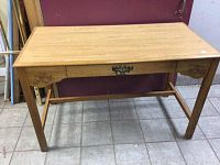 Full view of wooden desk showing rectangular top, legs, stretcher bar, and decorative carvings on sides.