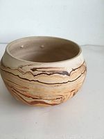 Side view of Nemadji pottery bowl showing earth-tone swirls and wide rounded shape