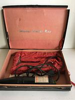 Photo of the open case containing the Master Violet Ray device and glass electrode lined in red velvet.