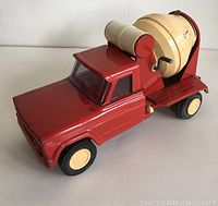 Side angle view of the red metal Tonka cement mixer toy truck showing the cab, cement mixer drum, and wheels