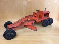 Front and side view of vintage metal toy road grader showing blade, wheels, and operator seat