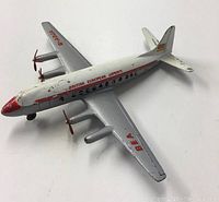 Top-down angled view of the metal toy airplane showing silver wings with red BEA lettering and four red propellers, white fuselage with 'British European Airways' in red and black windows along side
