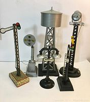Six vintage train accessories grouped together showing variety including water tower, rail signals, and street lamp.