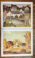 Two AJ Casson prints stacked vertically, showcasing the full artwork of rural village and countryside scenes