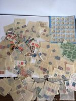 Large assortment of stamps displayed loosely and inside glassine envelopes on a white background, showing hundreds of stamps.