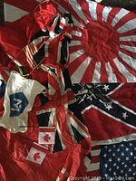 Photo showing multiple flags including the Rising Sun flag of Japan, the Union Jack, the Confederate battle flag, two small Canadian flags, an American flag, and a white flag with a blue emblem.